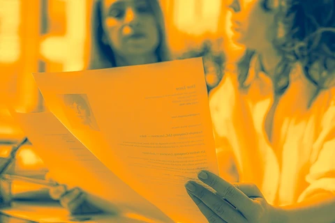 Two women looking at resumes with a yellow tint
